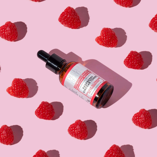 Raspberry Vinegar Toner bottle with fresh raspberries on a pink background, highlighting natural skincare for oily and blemish-prone skin.