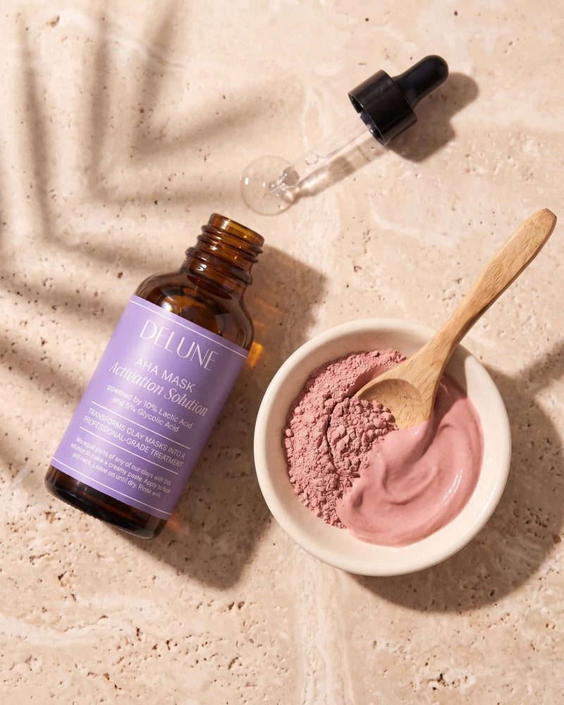 Delune AHA Mask Activation Solution with its dropper beside a dish of rose clay, half dry powder and half freshly activated paste
