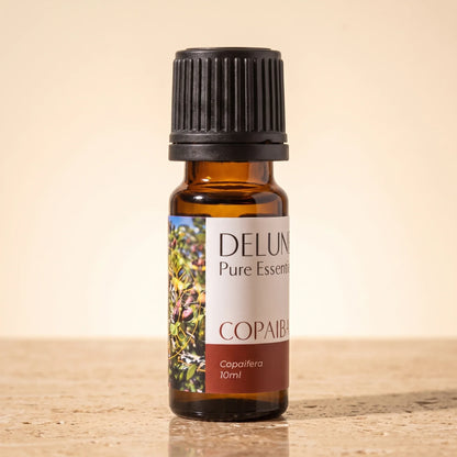 Delune Copaiba Pure Essential Oil, 10ml amber glass bottle on warm travertine stone