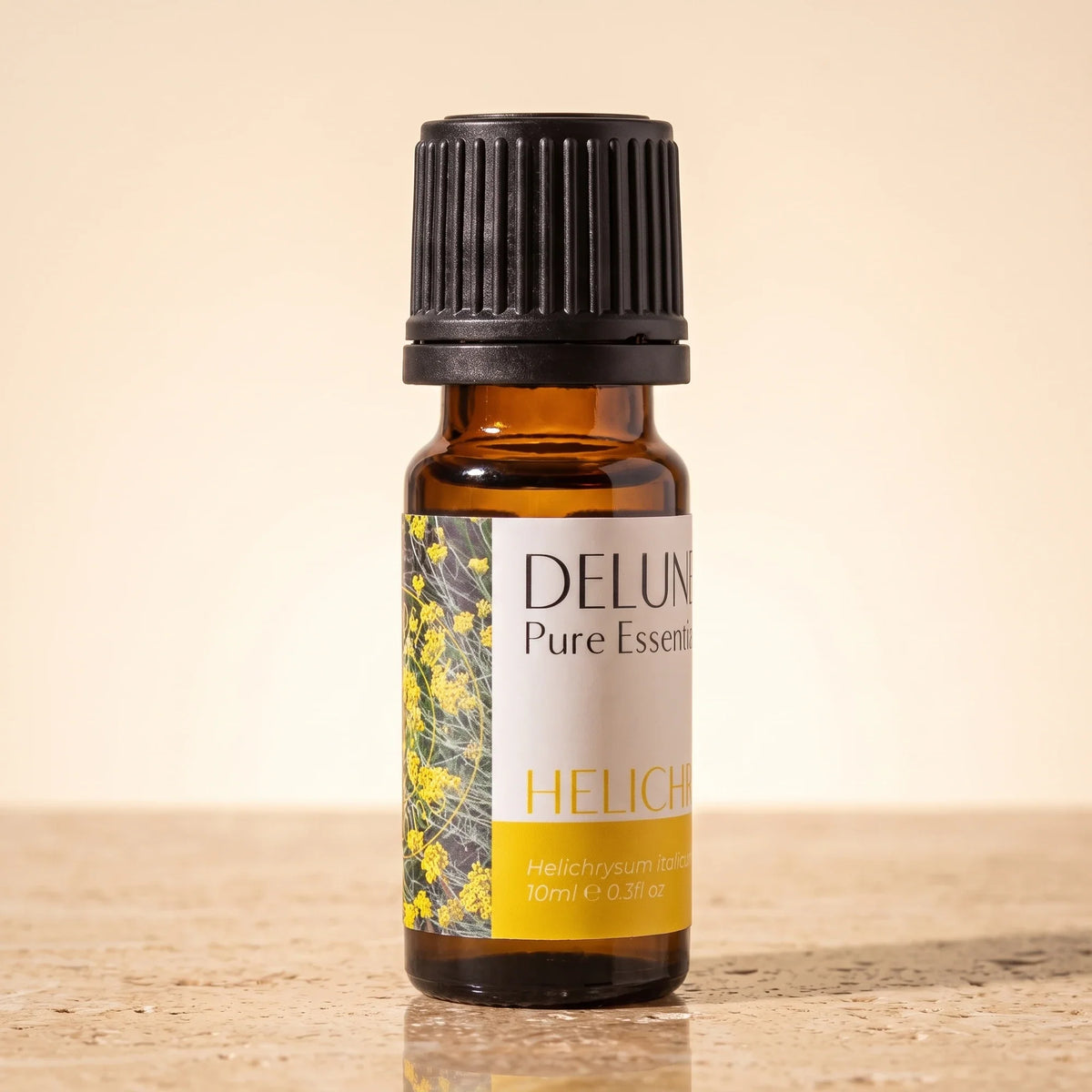 Delune Helichrysum (Immortelle) Pure Essential Oil, 10ml amber glass bottle on warm travertine stone