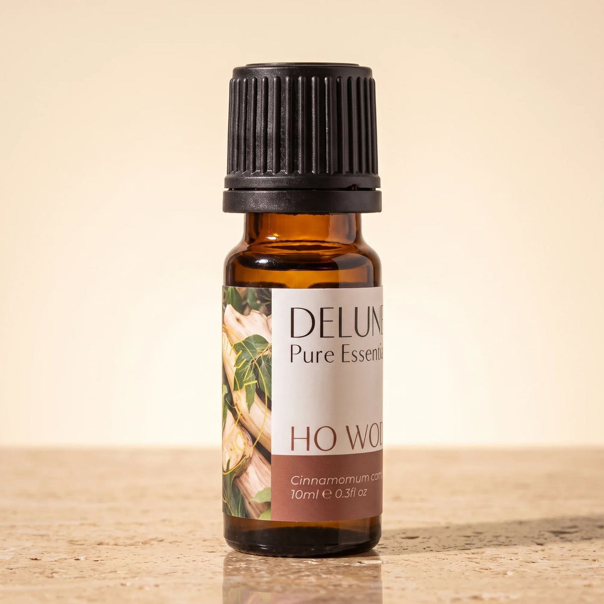 Delune Ho Wood Pure Essential Oil, 10ml amber glass bottle on warm travertine stone