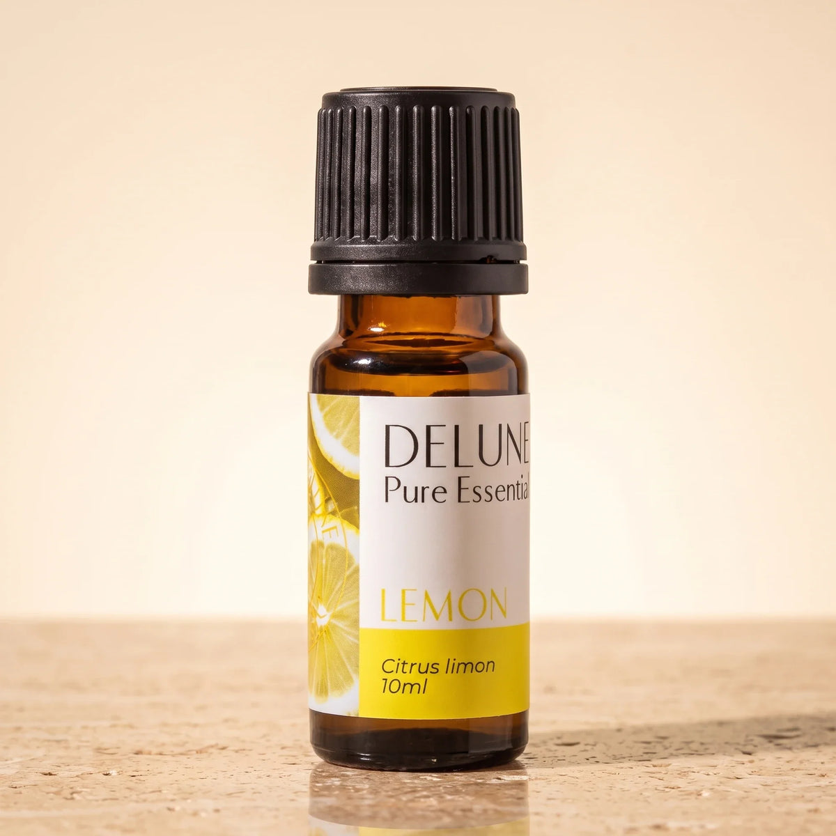Delune Lemon Pure Essential Oil, 10ml amber glass bottle on warm travertine stone