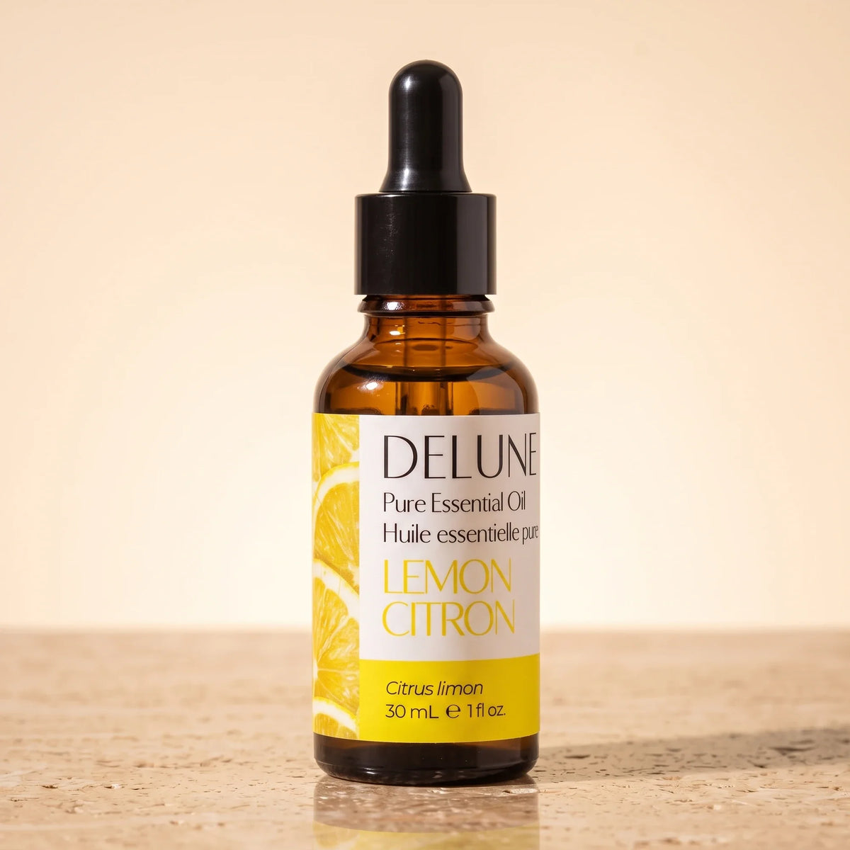 Delune Lemon Pure Essential Oil, 30ml amber glass dropper bottle on warm travertine stone