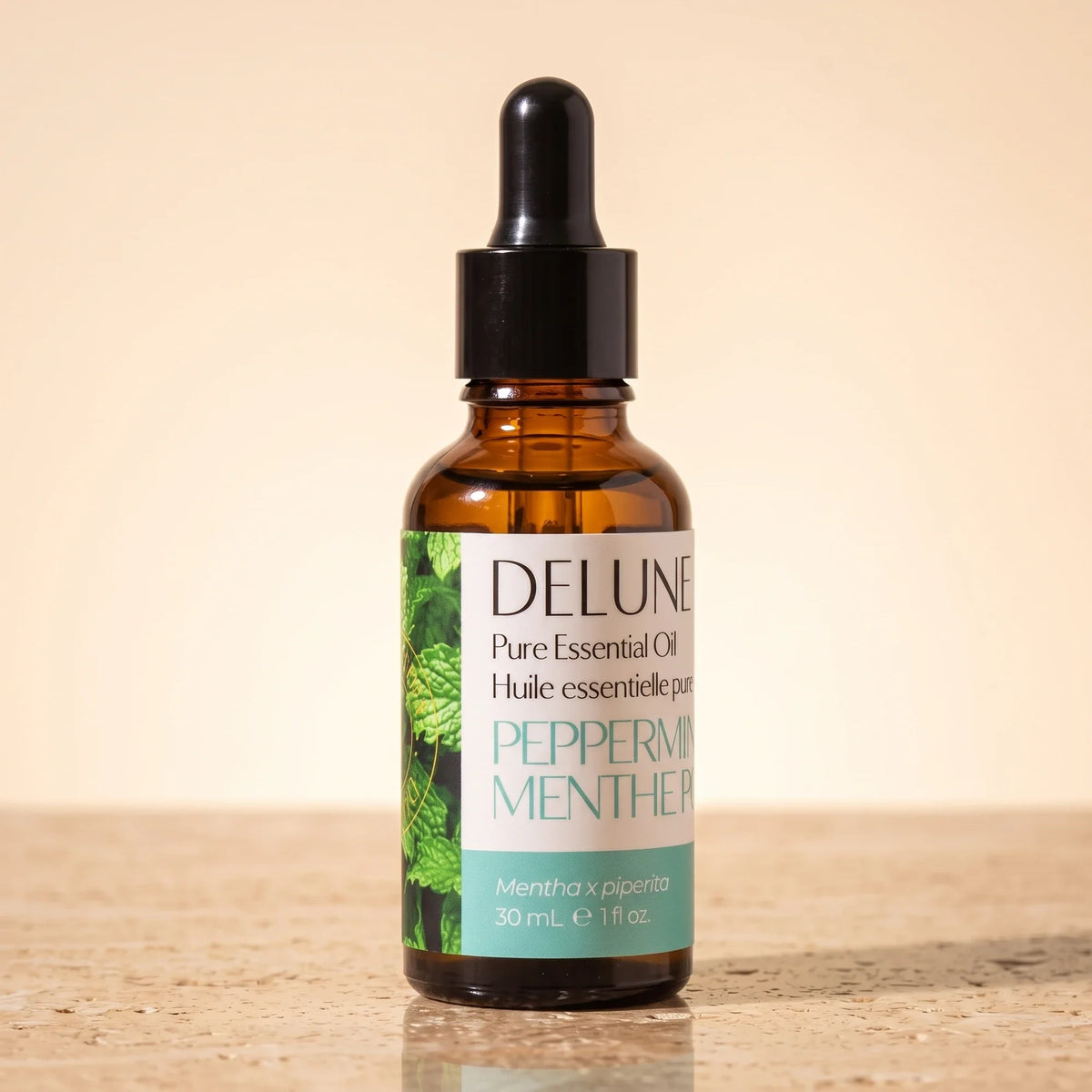 Delune Peppermint Pure Essential Oil, 30ml amber glass dropper bottle on warm travertine stone