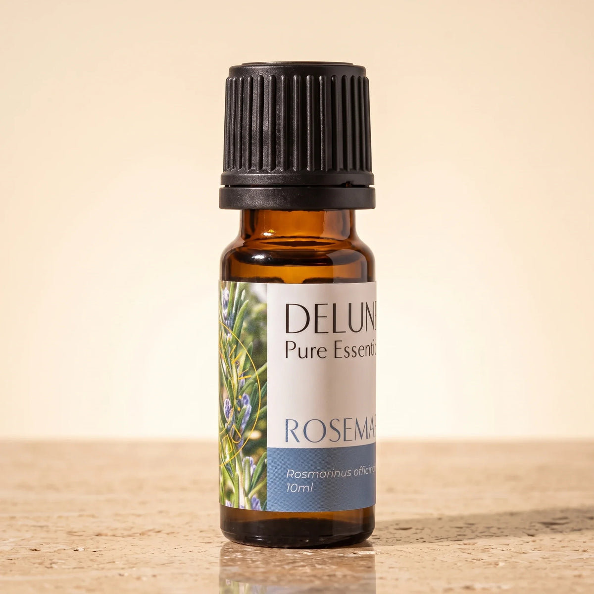 Delune Rosemary Pure Essential Oil, 10ml amber glass bottle on warm travertine stone