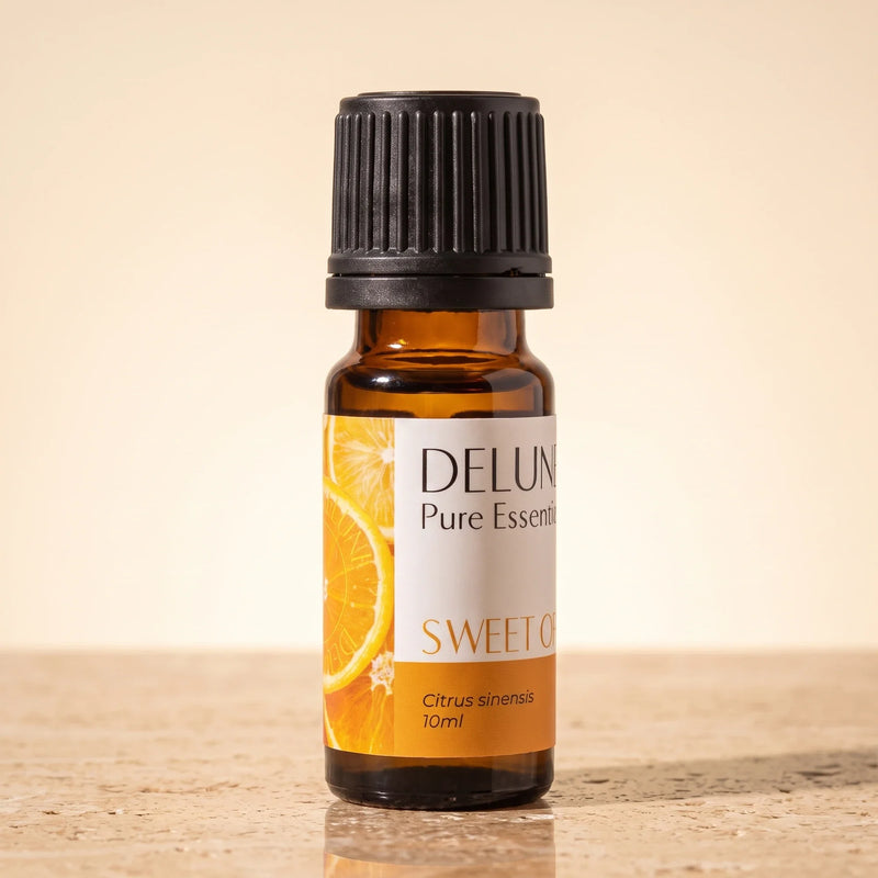 Delune Sweet Orange Pure Essential Oil, 10ml amber glass bottle on warm travertine stone