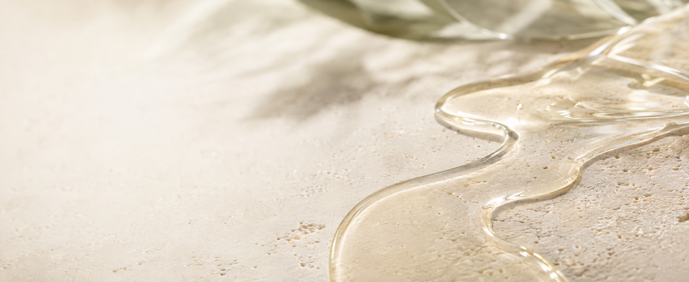 Skin Neutral facial oil flowing across pale travertine to represent the skin surface lipid layer