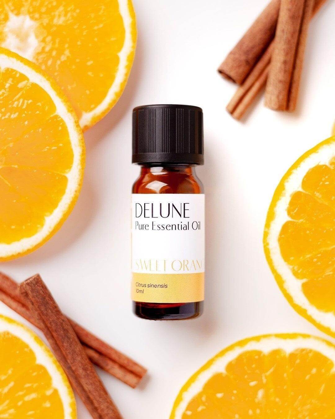 Sweet orange essential oil bottle with fresh orange slices and cinnamon sticks.