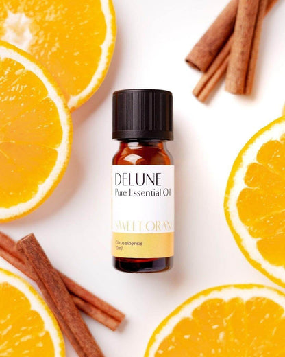 Sweet orange essential oil bottle with fresh orange slices and cinnamon sticks.